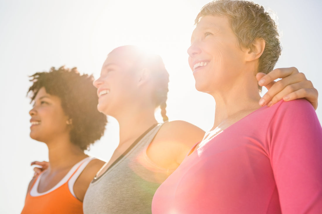 Three friends enjoying a sunny day, smiling together and looking off into the distance.